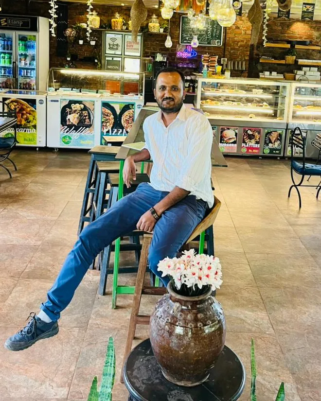 Sanjeev sitting on a stool in a café